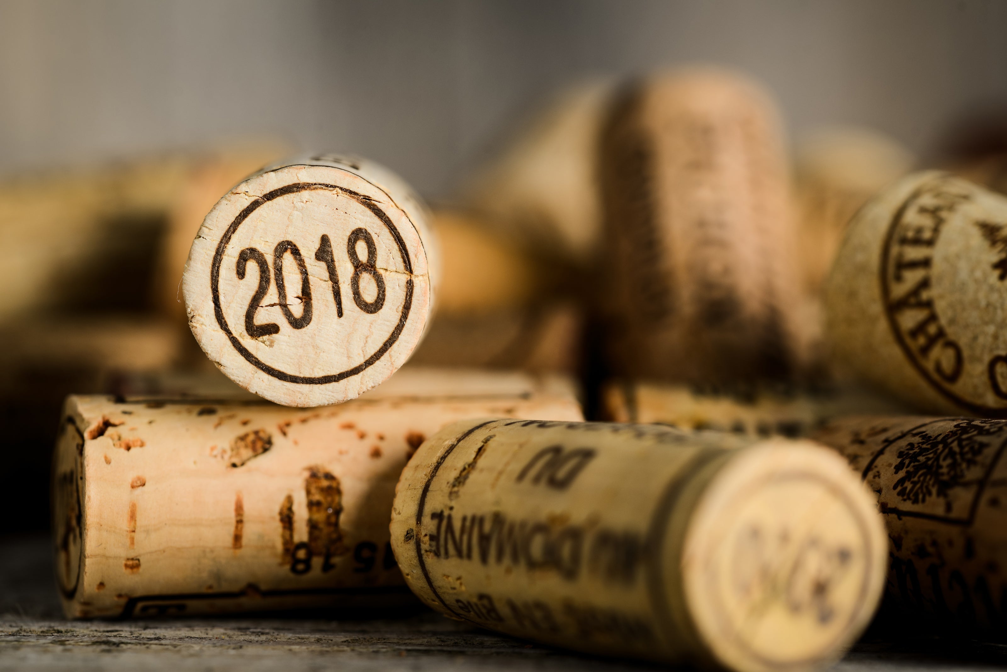 Close-up of wine corks with a prominent cork marked '2018' in focus, surrounded by other vintage wine corks.