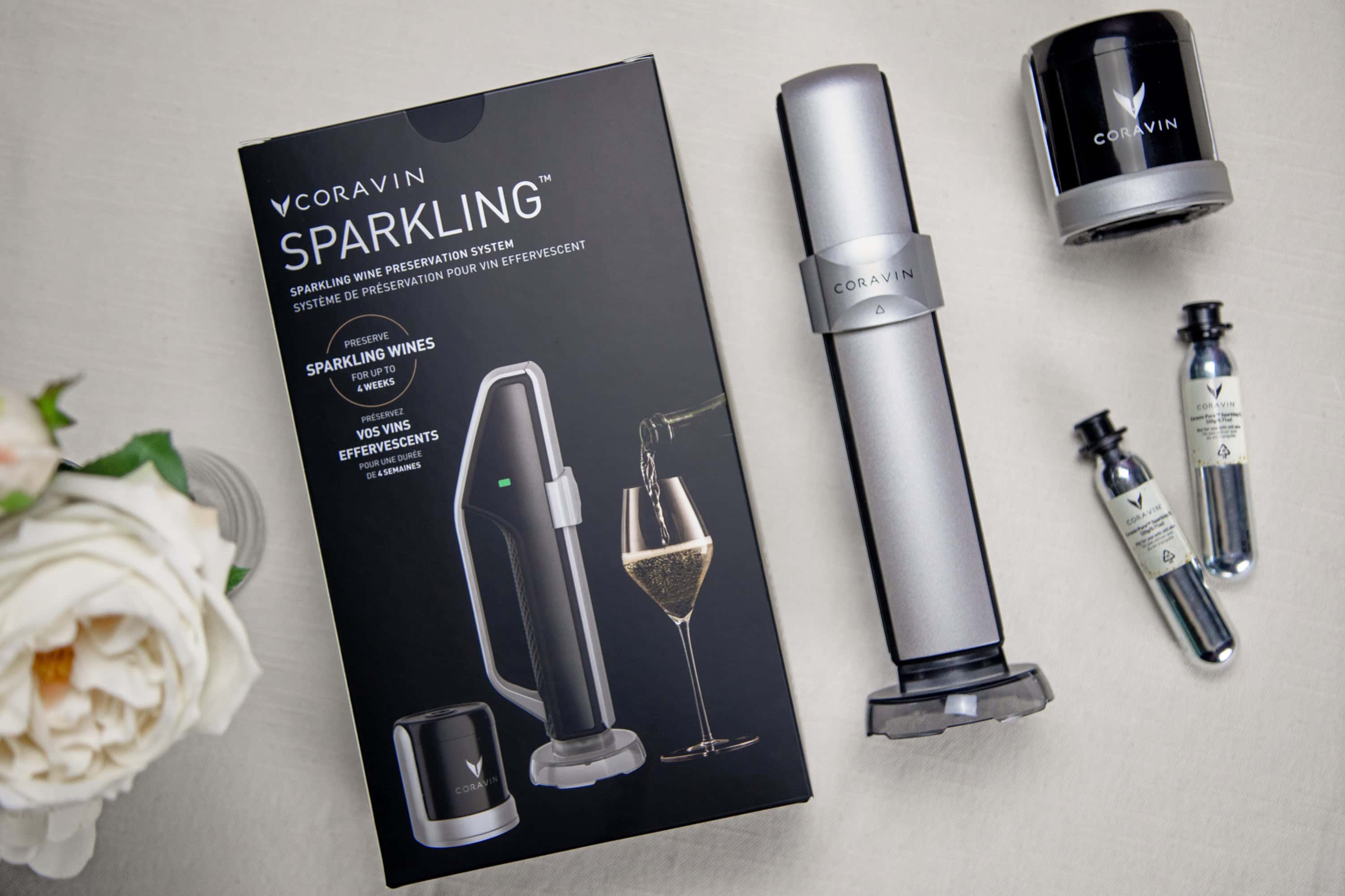 Coravin Sparkling Wine Preservation System with packaging, stopper, charger, and CO2 capsules on a light surface.